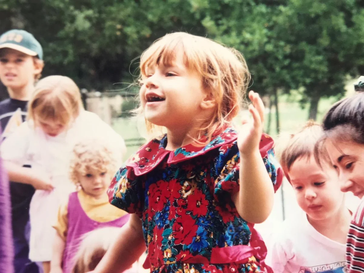 Zoe als Kind in São Paulo, lachend, buntes Blumenkleid
