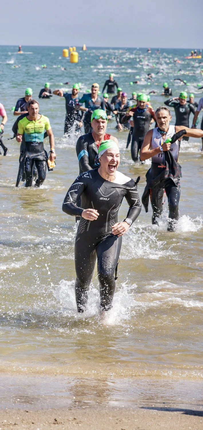 Zoe storming out of the sea in Cervia, laughing, wetsuit, triathlon swim exit
